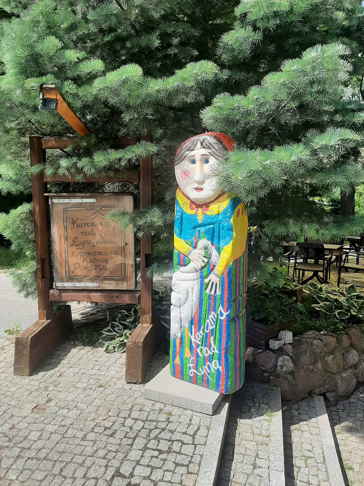 Entrance to Karczma Nad Łyną — timber sign and folk figure